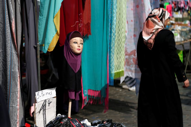 &copy; Reuters. إمرأة تمشي أمام عارضة أزياء ترتدي حجاب في بروكسل ببلجيكا في صورة من أرشيف رويترز.