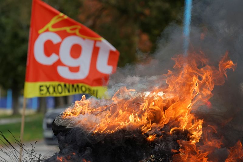 © Reuters. Un drapeau du syndicat CGT et des pneus enflammés devant la raffinerie de pétrole ExxonMobil, à Port-Jérôme-sur-Seine, France. /Photo prise le 12 octobre 2022/REUTERS/Pascal Rossignol