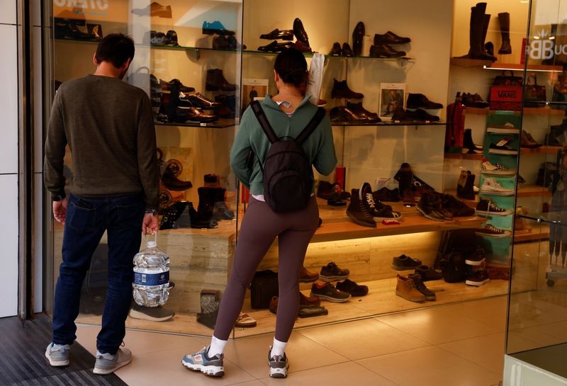 &copy; Reuters. A couple carries a bottle of water and a loaf of bread as they watch the display of a shoe shop in Ronda, Spain, October 13, 2022. REUTERS/Jon Nazca