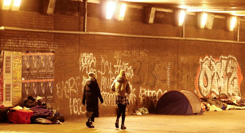 &copy; Reuters. FILE PHOTO: Pedestrians walk past homeless people under a bridge at the Charlottenburg railway station, which has become a fixed meeting point for many homeless people to place their belongings, amid the coronavirus disease (COVID-19) pandemic during lock