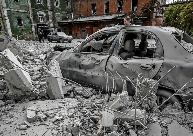 © Reuters. A woman stands near her destroyed car near an old mill, built around 1885, also destroyed during a Russian missile attack in Zaporizhzhia, Ukraine October 14, 2022. REUTERS/Stringer