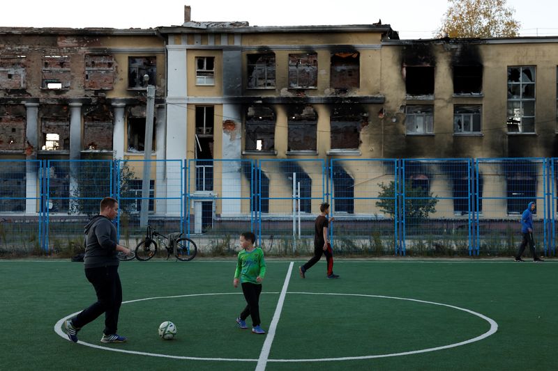 &copy; Reuters. Foto del viernes de un grupo de personas jugando al fútbol en un campo de la Escuela N 134, que fue destruida por los ataques rusos, en Járkov. 
Oct 14, 2022. REUTERS/Clodagh Kilcoyne