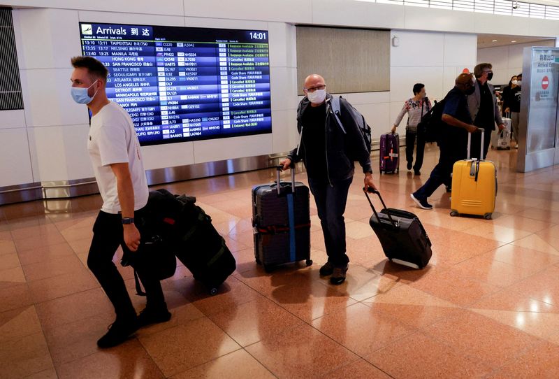 &copy; Reuters. FILE PHOTO: oreign travellers walk upon their arrival at the Haneda International Airport, on the first day after Japan opened its doors to tourists after closing them for two-and-a-half years due to travel restrictions sparked by the outbreak of the coro