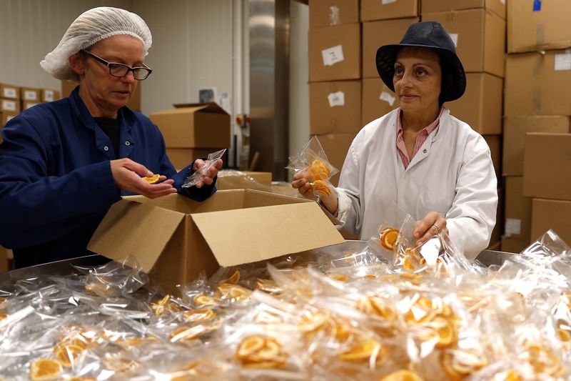 &copy; Reuters. Founder and CEO of Nim's Fruit Crisps, Nimisha Raja, helps fellow workers pack dried oranges at her factory, in Sittingbourne, Britain, October 17, 2022. REUTERS/Peter Nicholls