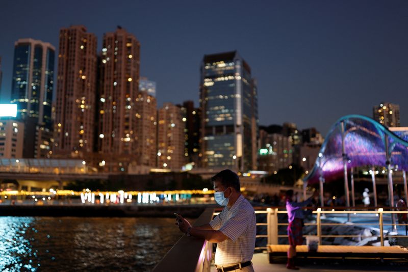 © Reuters. A man checks his phone at a promenade during sunset in Hong Kong, China October 12, 2022. REUTERS/Tyrone Siu