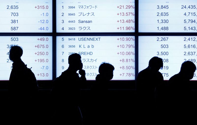 &copy; Reuters. Passersby are silhouetted as they walk past in front of an electric stock quotation board outside a brokerage in Tokyo, Japan October 18, 2022  REUTERS/Issei Kato