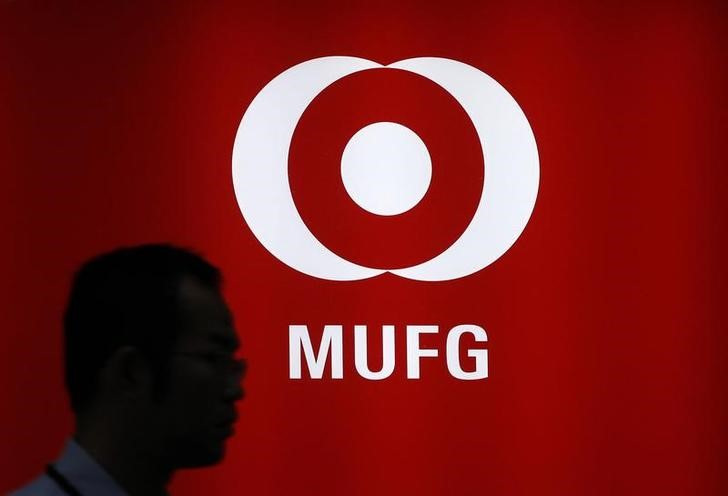 © Reuters. A man walks past a logo of Mitsubishi UFJ Financial Group Inc. (MUFG) in Tokyo. REUTERS/Toru Hanai 