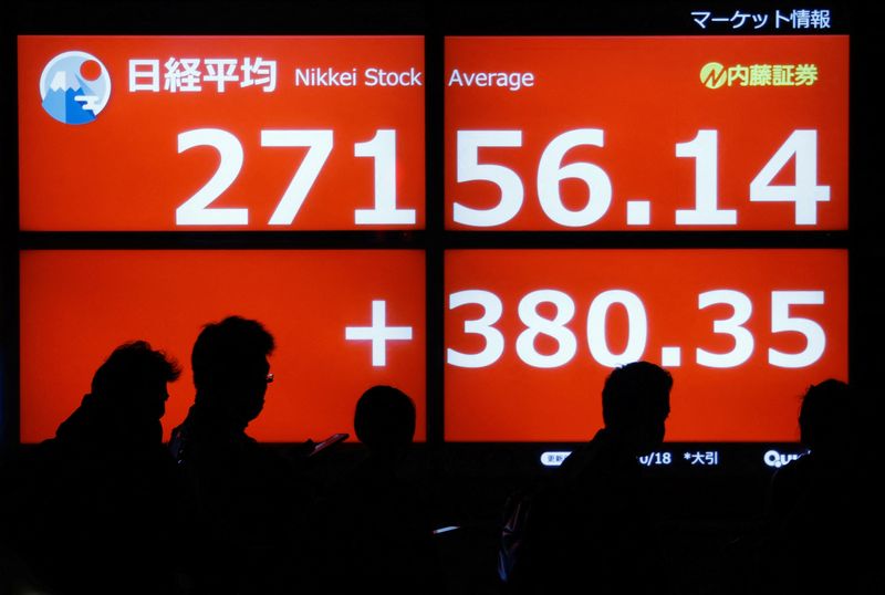 &copy; Reuters. FILE PHOTO: Passersby are silhouetted as they walk past in front of an electric monitor displaying the Japan's Nikkei share average outside a brokerage in Tokyo, Japan October 18, 2022  REUTERS/Issei Kato