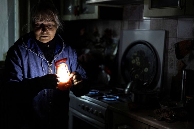 © Reuters. ウクライナ気象当局は２０日、今冬の天候が例年に比べ温暖になるとの予報を発表した。写真はガスコンロで部屋を温める女性。９月２２日、ハリコフで撮影（２０２２年　ロイター/Umit Bektas）