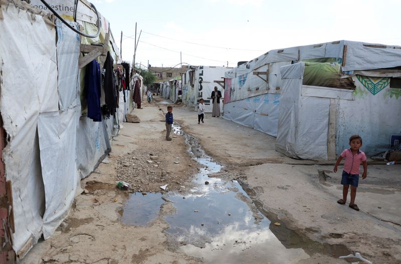 &copy; Reuters. أطفال يقفون بالقرب من ممر مياه في مخيم غير رسمي للاجئين السوريين في قب إلياس بسهل البقاع في لبنان بتاريخ 18 أكتوبر تشرين الأول 2022. تصوير: محمد 