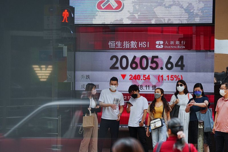 © Reuters. Pessoas aguardam em frente a painel mostrando índice de ações em Hong Kong, China 
19/07/2022
REUTERS/Lam Yik