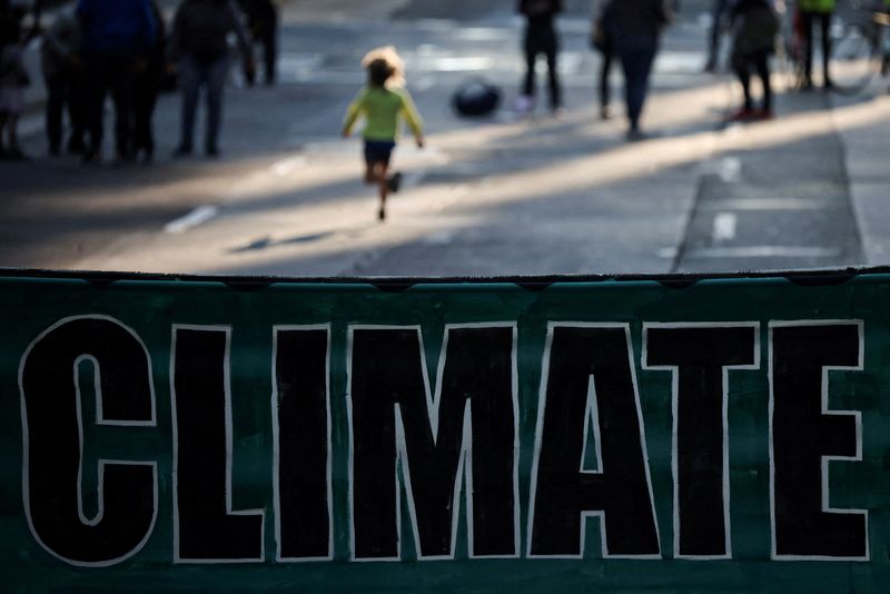 © Reuters. FILE PHOTO: A child runs as climate change activists gather to protest outside of BlackRock headquarters ahead of the 2021 United Nations Climate Change Conference (COP26), in San Francisco, California, U.S., October 29, 2021. REUTERS/Carlos Barria