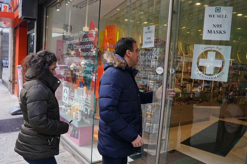 &copy; Reuters. FILE PHOTO: People walk into a pharmacy to buy N95 masks in advance of the potential coronavirus outbreak, in the Manhattan borough of New York City, New York, U.S., February 27, 2020. REUTERS/Carlo Allegri