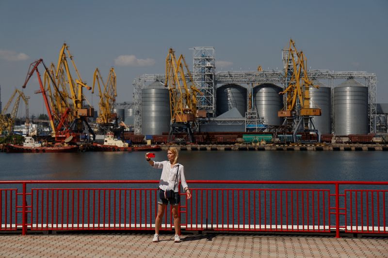 &copy; Reuters. امرأة تلتقط صورة ذاتية مع محطة حبوب في الخلفية في ميناء أوديسا يوم 19 أغسطس آب 2022. تصوير: فالنتين أوجيرنكو - رويترز