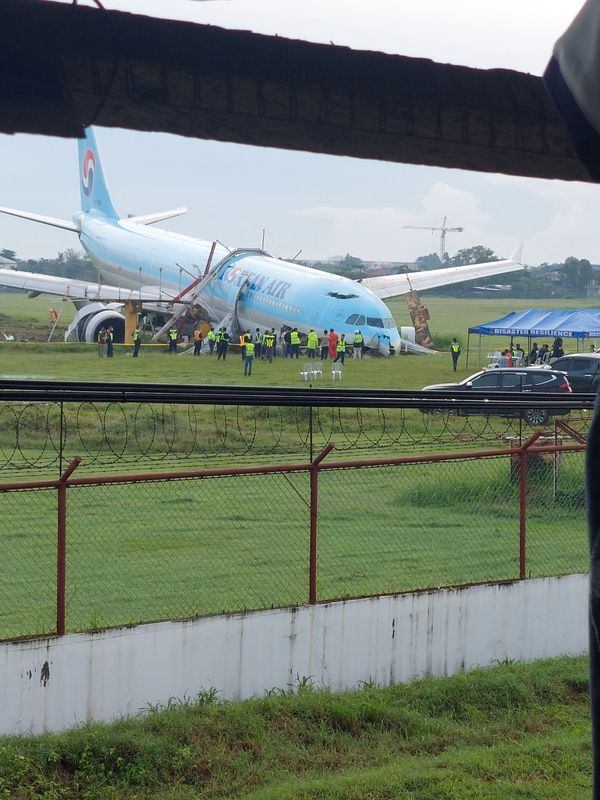 © Reuters. Response crews gather around a Korean Air Airbus A330 widebody flying from Seoul to Cebu, which tried to land twice in poor weather before it overran the runway on the third attempt on Sunday, in Lapu-Lapu City, Cebu, Philippines October 24, 2022 in this picture obtained from social media. Randyl Dungog/via REUTERS