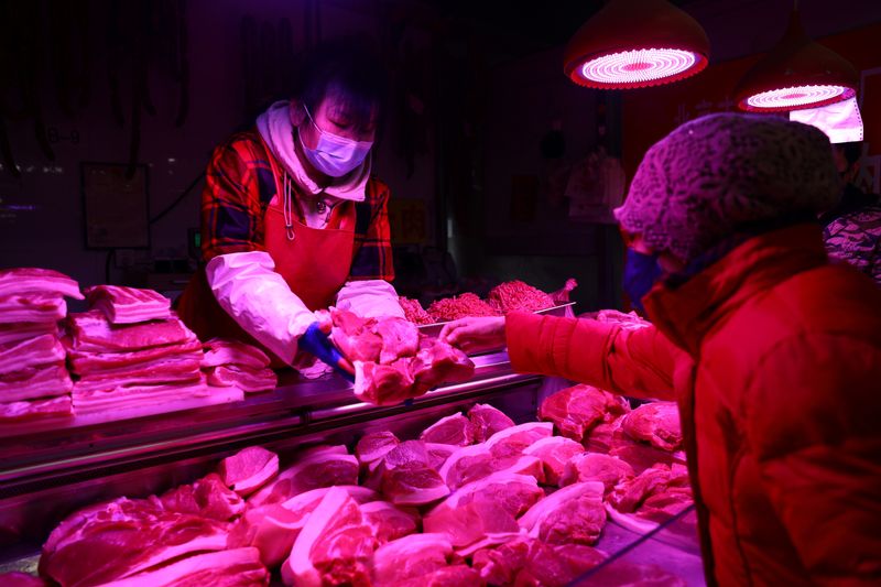 &copy; Reuters. FILE PHOTO: A customer buys pork at a meat stall inside a morning market in Beijing, China January 14, 2022. Picture taken January 14, 2022. REUTERS/Tingshu Wang