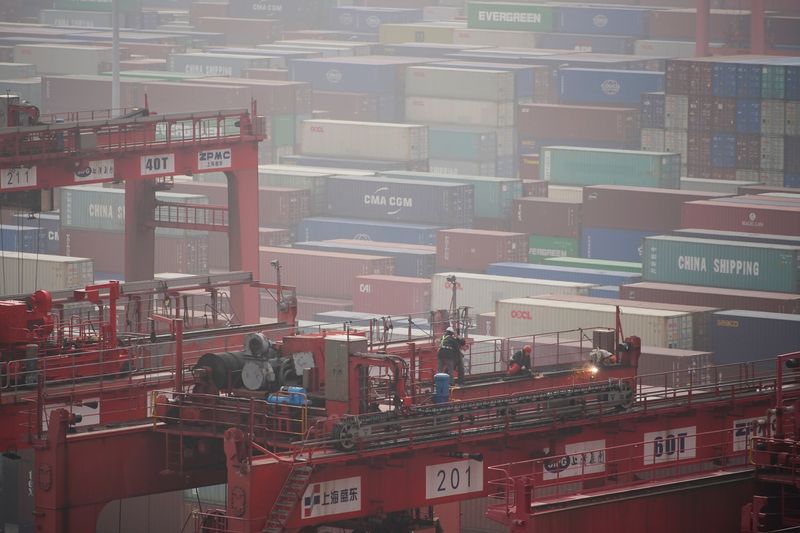 &copy; Reuters. FILE PHOTO: Workers are seen on a crane above containers at the Yangshan Deep Water Port in Shanghai, China January 13, 2022. REUTERS/Aly Song