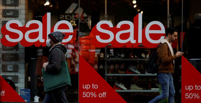 &copy; Reuters. FILE PHOTO: People walk past sale signs on the window of a shoe shop in Manchester, Britain, December 28, 2021. REUTERS/Phil Noble