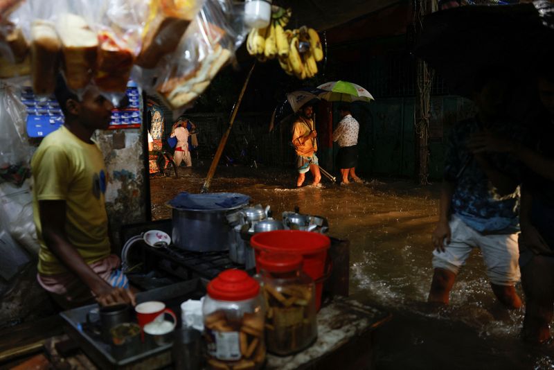 &copy; Reuters. أفراد يخوضون في مياه أمطار غزيرة هطلت قبل إعصار سيترانج في دكا يوم الاثنين. تصوير: محمد بونير حسين - رويترز. 