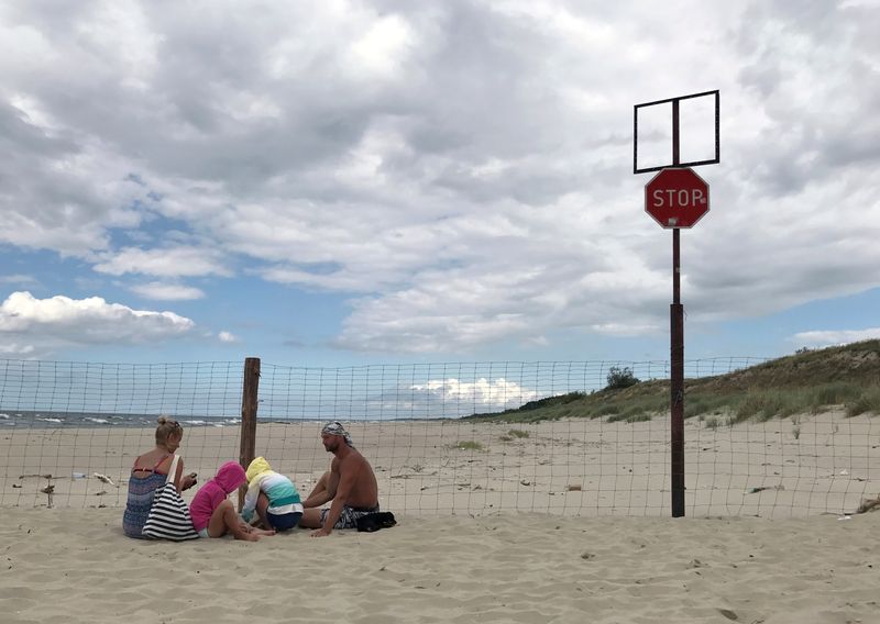 &copy; Reuters. FOTO DE ARCHIVO: Una familia sentada en una playa junto a la valla que divide Polonia del exclave ruso de Kaliningrado, en Krynica Morska, Polonia, el 6 de agosto de 2017. REUTERS/Radu Sigheti