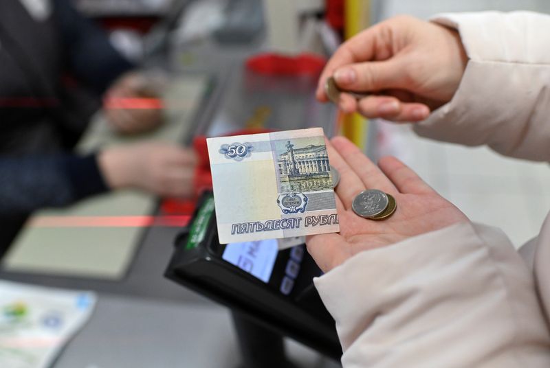 &copy; Reuters. Local resident Maria Komissarova, 29, holds Russian rouble coins and a 50-rouble banknote as she buys food at a supermarket in the Siberian town of Tara in the Omsk region, Russia, December 14, 2021. REUTERS/Alexey Malgavko/Files