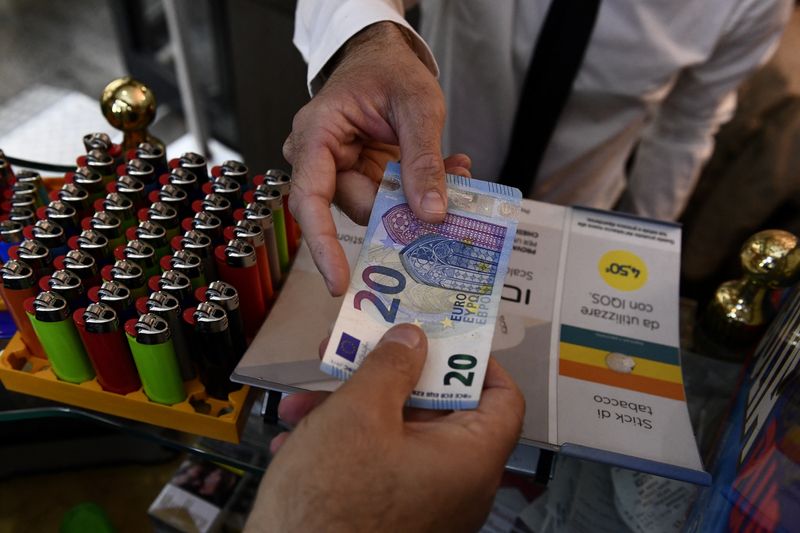 &copy; Reuters. FILE PHOTO: A man uses cash to pay for items while shopping in Milan, Italy, October 2, 2020. Picture taken October 2, 2020. REUTERS/Flavio Lo Scalzo