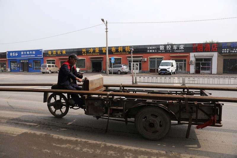 &copy; Reuters. FILE PHOTO: A worker rides on a vehicle carrying pipes past an industrial park in Shenyang, Liaoning province, China, September 30, 2021. REUTERS/Tingshu Wang/File Photo