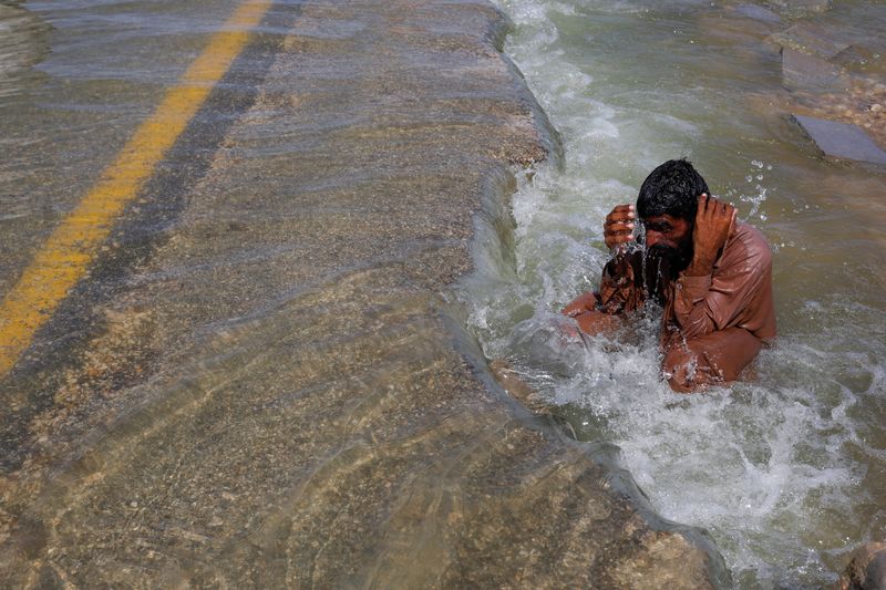 &copy; Reuters. A displaced man cools off to avoid heat on flooded highway, following rains and floods during the monsoon season in Sehwan, Pakistan, September 16, 2022. REUTERS/Akhtar Soomro