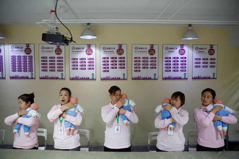 © Reuters. FOTO DE ARCHIVO: Estudiantes de Ayi University, un programa de entrenamiento para asistentes domésticos, practica con muñecos bebés durante un curso de ciudado en Pekín, China, 5 de diciembre del 2018.  REUTERS/Thomas Peter/Foto de Archivo