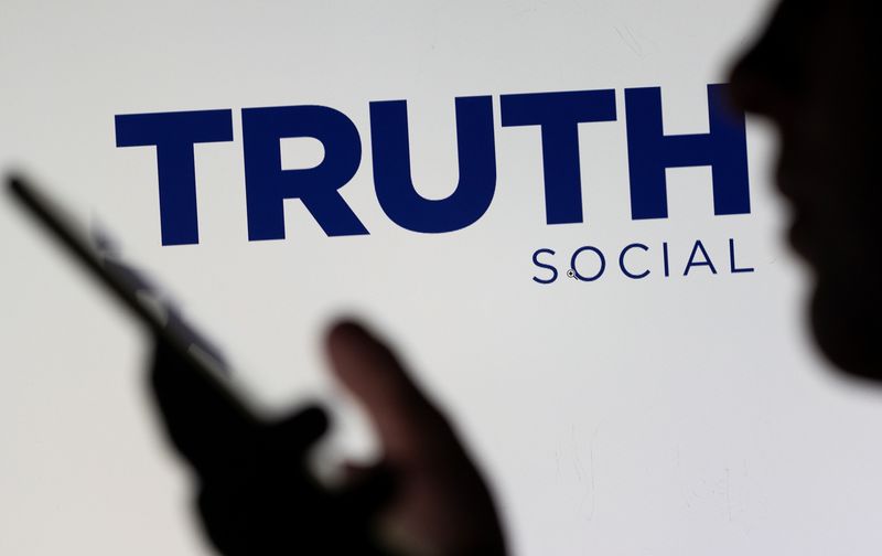 &copy; Reuters. FILE PHOTO: The Truth social network logo is seen displayed behind a woman holding a smartphone in this picture illustration taken February 21, 2022. REUTERS/Dado Ruvic/Illustration