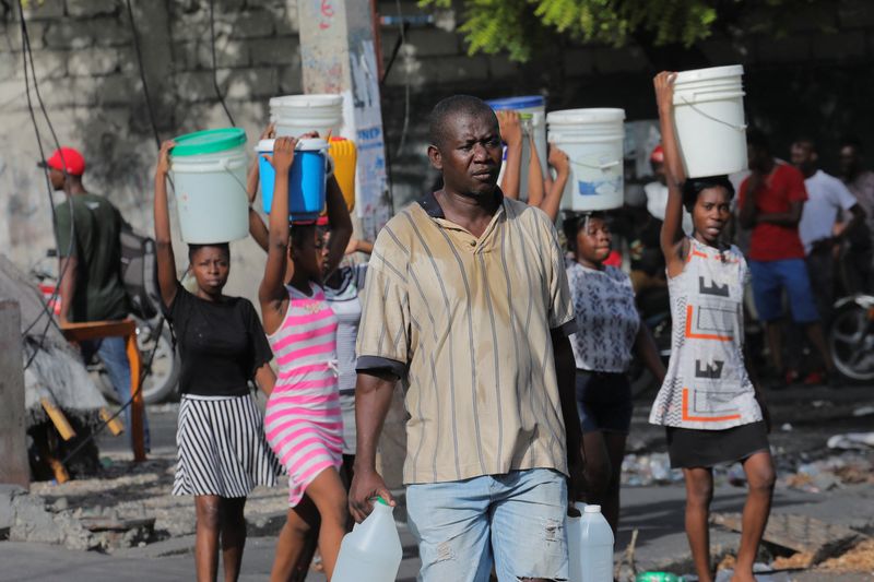 &copy; Reuters. People carry containers with water amid water shortages due to daily protests against high gasoline prices and crime, and to stock up for Storm Fiona approaching in the Caribbean region, in Port-au-Prince, Haiti. September 17, 2022. REUTERS/Ralph Tedy Ero