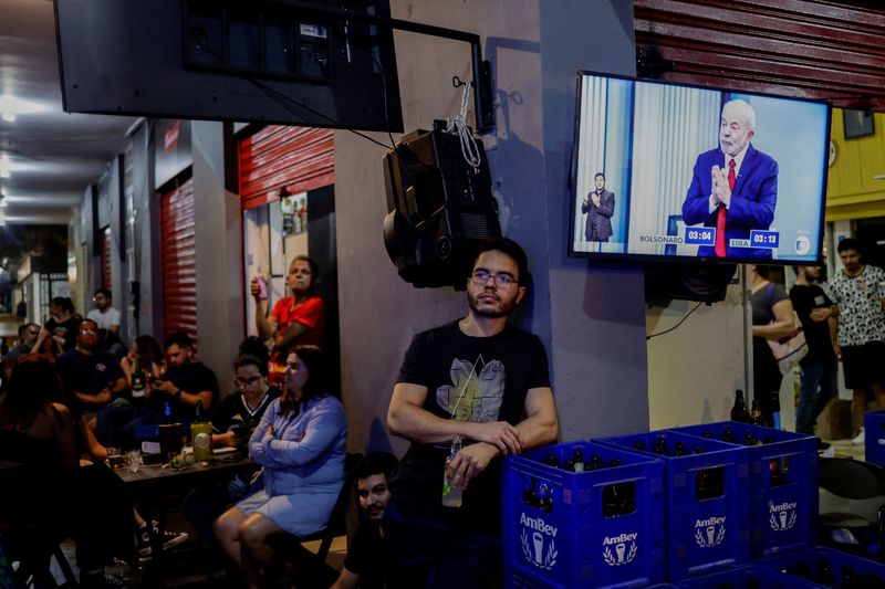 &copy; Reuters. Des personnes observent un débat avant le second tour de l'élection entre le président brésilien et candidat à sa réélection Jair Bolsonaro et l'ancien président et actuel candidat Luiz Inacio Lula da Silva, dans un bar de Brasilia, au Brésil. /P