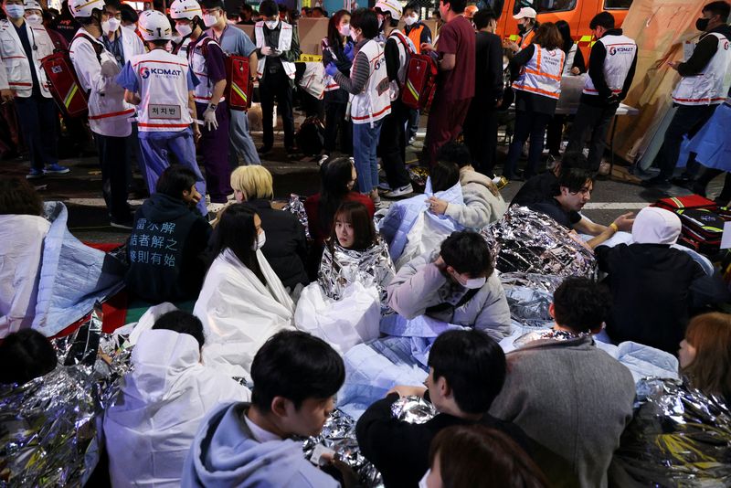 &copy; Reuters. Personas sentadas en la calle tras ser rescatadas, en el lugar donde decenas de personas resultaron heridas en una estampida durante un festival de Halloween en Seúl, Corea del Sur. 29 de octubre de 2022. REUTERS/Kim Hong-ji