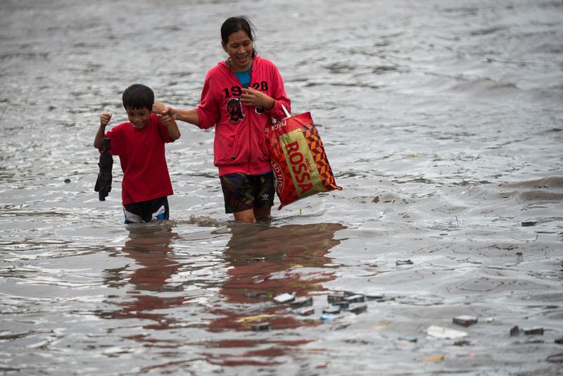 &copy; Reuters. A mother and a child wade through a flooded road following heavy rains brought by Tropical Storm Nalgae, in Las Pinas City, Metro Manila, Philippines, October 30, 2022. REUTERS/Lisa Marie David