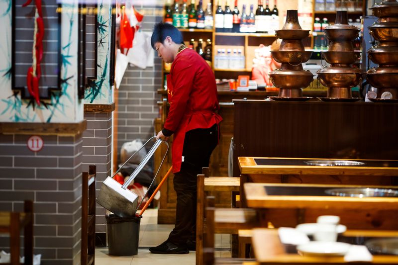 &copy; Reuters. FILE PHOTO: A waiter cleans the floor of a restaurant after closing hours in Beijing, China October 28, 2019. Picture taken October 28, 2019. REUTERS/Thomas Peter