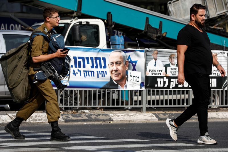 &copy; Reuters. A soldier walks past election campaign banners depicting former Israeli Prime Minister Benjamin Netanyahu and other politicians by a train station in Tel Aviv, Israel October 30, 2022. REUTERS/Corinna Kern