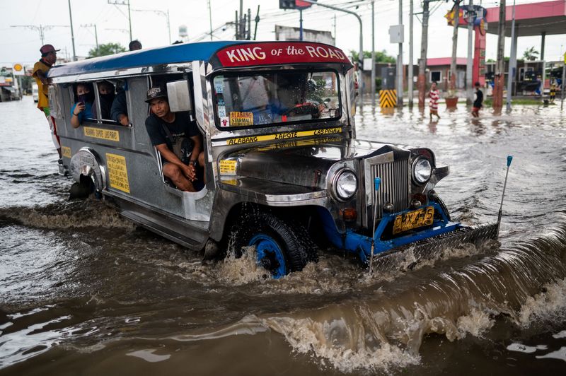 © Reuters. FILE PHOTO: A jeepney wades through a flooded road following heavy rains brought by Tropical Storm Nalgae, in Las Pinas City, Metro Manila, Philippines, October 30, 2022. REUTERS/Lisa Marie David