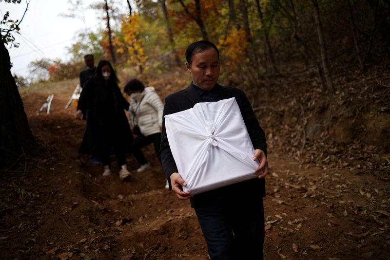 © Reuters. Jung Hae-moon, 62, father of Jung Joo-hee, 30, who was one of the victims of a crowd crush that happened during Halloween festivities, leaves his daughter's grave holding her portrait, in Namyangju, South Korea, November 3, 2022. REUTERS/Kim Hong-Ji
