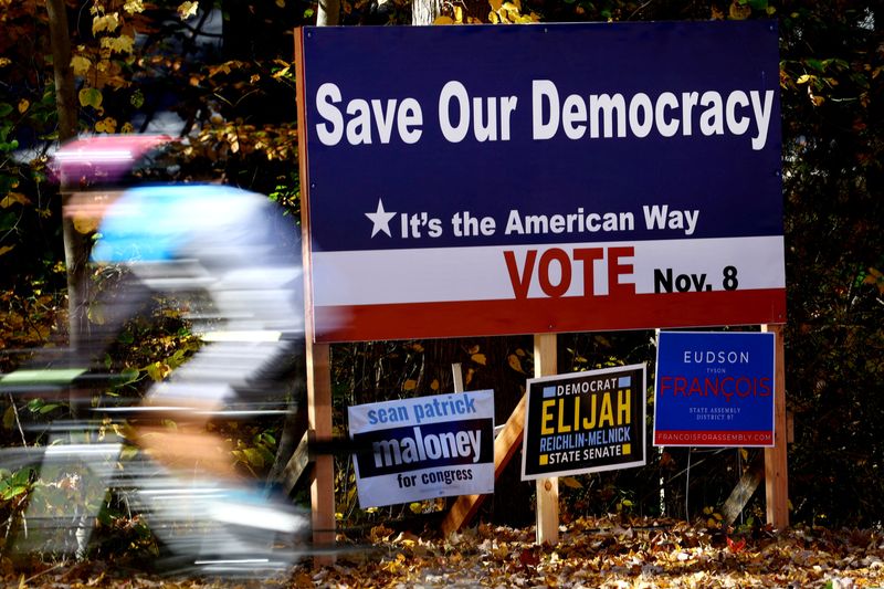 © Reuters. FILE PHOTO: FILE PHOTO: A cyclist rides past political signs ahead of the November 8, 2022, U.S. midterm elections in the New York City suburb of Palisades, New York, U.S., October 27, 2022. REUTERS/Mike Segar/File Photo/File Photo