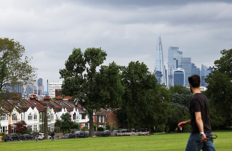 &copy; Reuters. FILE PHOTO: The city of London's financial district can be seen in the distance as a person walks near a row of residential housing in south London, Britain, August 6, 2021. REUTERS/Henry Nicholls/File Photo