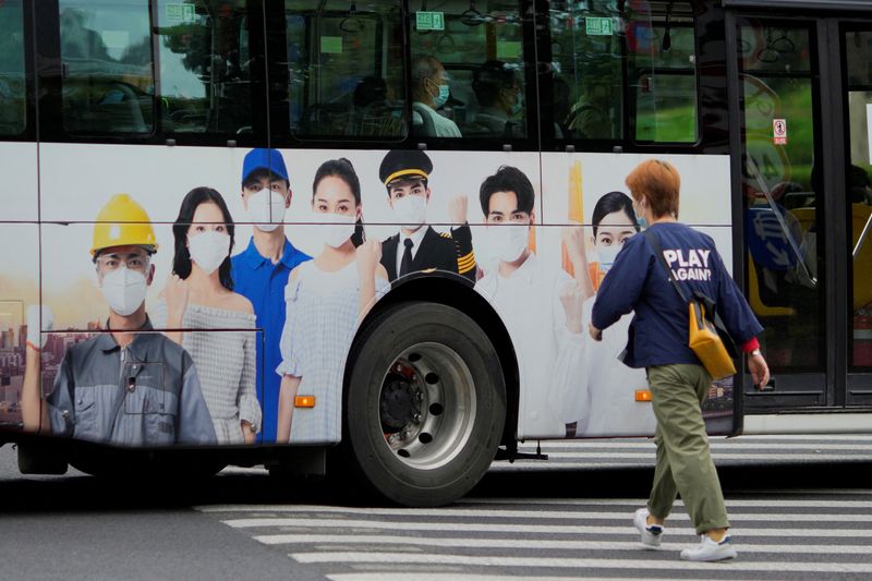 © Reuters. FILE PHOTO: A woman crosses a street as a bus with an advertisement on epidemic prevention passes by, following the coronavirus disease (COVID-19) outbreak, in Shanghai, China, September 28, 2022. REUTERS/Aly Song