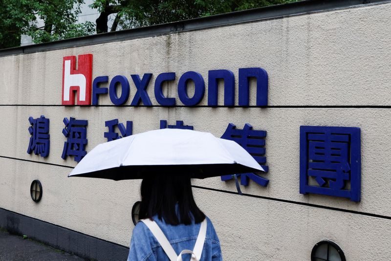 © Reuters. FILE PHOTO: A woman carrying an umbrella walks past the logo of Foxconn outside a company's building in Taipei, Taiwan October 31, 2022. REUTERS/Carlos Garcia Rawlins/File Photo