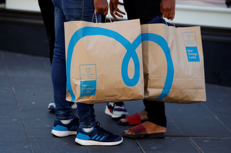 © Reuters. FILE PHOTO: Shoppers holding newly environmentally themed bags stand outside a Primark store in Liverpool, Britain, September 15, 2021. REUTERS/Phil Noble