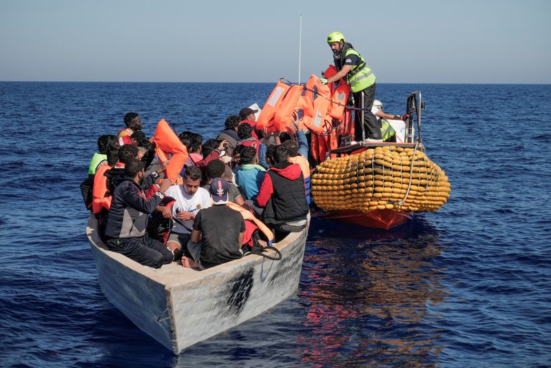 &copy; Reuters. FILE PHOTO: Crew members of NGO rescue ship 'Ocean Viking' give lifejackets to migrants on an overcrowded boat in the Mediterranean Sea, October 25, 2022. Camille Martin Juan/Sos Mediterranee/Handout via REUTERS