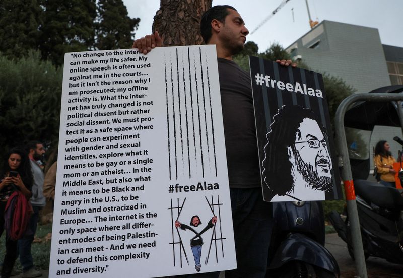 &copy; Reuters. FILE PHOTO: A demonstrator holds placards as he demands the release of Egyptian-British hunger striker Alaa Abd el-Fattah near the British Embassy in Beirut, Lebanon November 7, 2022. REUTERS/Mohamed Azakir