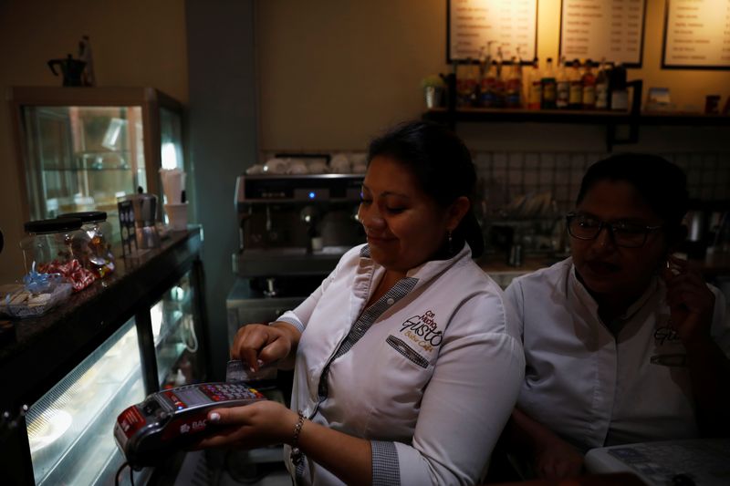&copy; Reuters. A cashier processes a customer's credit card during payment at a cafe in San Salvador, El Salvador April 4, 2019. REUTERS/Jose Cabezas