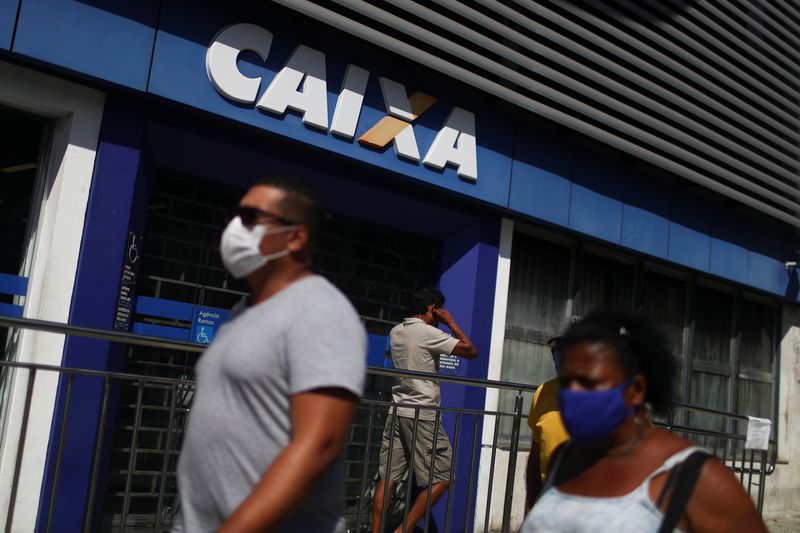 &copy; Reuters. Pessoas usando máscaras de proteção facial passam em frente à agência da Caixa no Rio de Janeiro
05/05/2020 REUTERS/Pilar Olivares