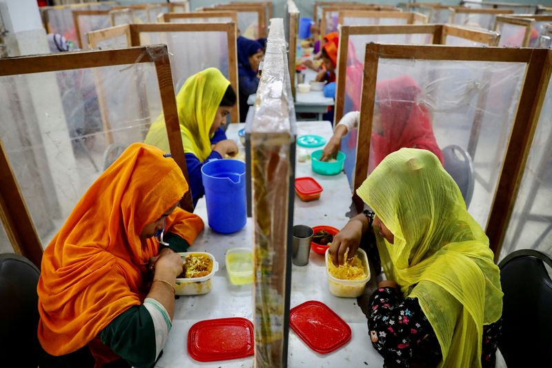 © Reuters. FILE PHOTO: Employees dine between polythene sheets, as a safety measure to reduce the spread of coronavirus disease (COVID-19), at The Civil Engineering Limited garment factory in Dhaka, Bangladesh, August 17, 2021. REUTERS/Mohammad Ponir Hossain/File Photo