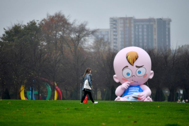 &copy; Reuters. A woman walks past a giant baby balloon inflated by Climate Change activists in the rain at Glasgow Green as the UN Climate Change Conference (COP26) takes place, in Glasgow, Scotland, Britain, November 8, 2021. REUTERS/Dylan Martinez