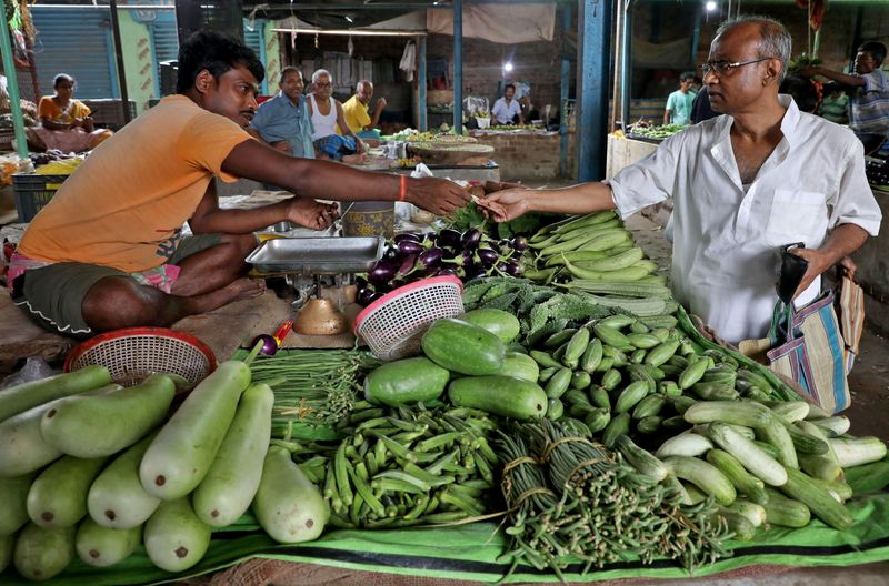 &copy; Reuters. FILE PHOTO: Nikhil Kumar Mondal, 65, a retired school headmaster, buys vegetables from a vendor at a market on the outskirts of Kolkata, India, May 20, 2022. REUTERS/Rupak De Chowdhuri